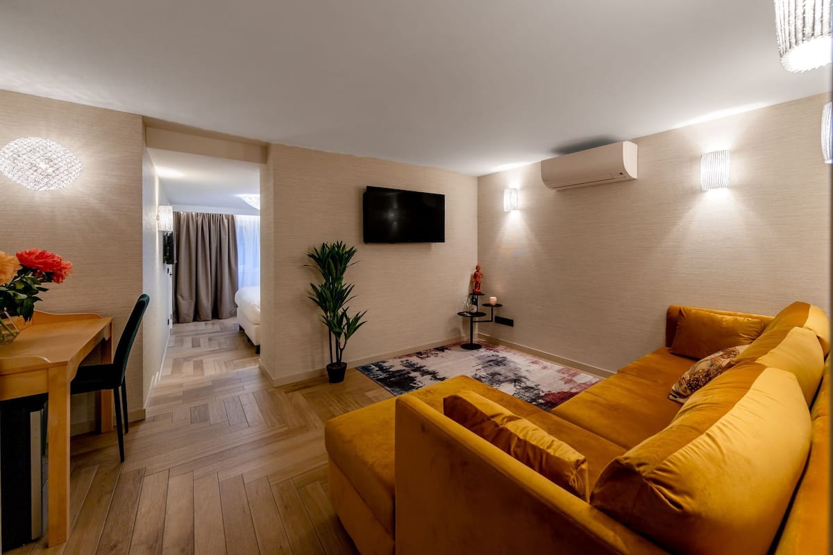 Een moderne woonkamer met een bank, een televisie en een eethoek met een tafel en stoelen.