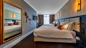 Een hotelkamer met twee bedden, een grote spiegel, een televisie en een bureau met een stoel.