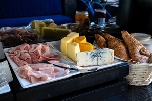 Une planche de charcuterie avec différentes sortes de viandes, de fromages et du pain, disposée sur une table.