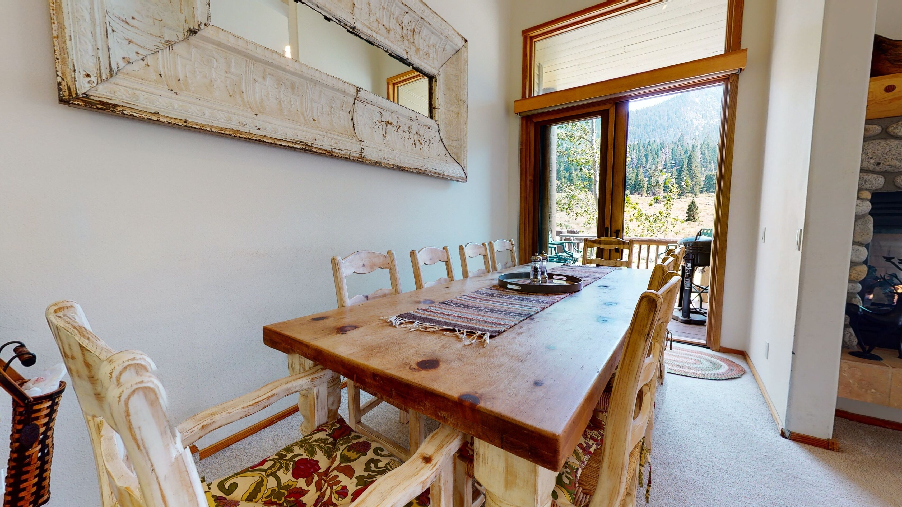Un coin repas avec une table en bois, six chaises et un grand miroir au mur.