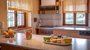 Una cocina con encimera de granito, una cesta de frutas, una taza de cerámica y diversos utensilios de cocina.