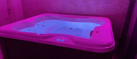 A hot tub with a control panel, set against a textured wall.