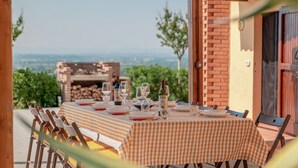 Un área de comedor al aire libre con mantel a cuadros, sillas y vistas al campo.