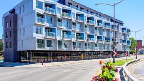 A modern multi-story building with balconies, large windows, and a ground-level entrance. - The Kaméléon, The hut (Québec City)