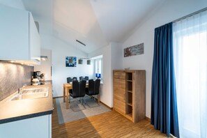 A modern kitchen with a sink and countertop, a dining area with a table and chairs, and a wooden cabinet.