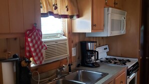 Una cocina compacta con armarios de madera, un microondas, una estufa y un lavabo.