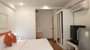 Una habitación de hotel con cama, televisión, escritorio y aire acondicionado.