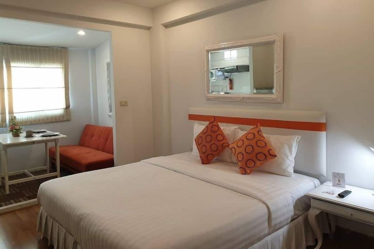 Una habitación de hotel con cama, escritorio, silla y espejo.