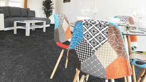 A modern living room with a grey sofa, a coffee table, and a dining area with patterned chairs. - Toothbrush Apartments - Ipswich Nr Train - Ranelagh Rd (Ipswich)
