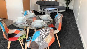 A dining area with a round glass table set for four, surrounded by colorful chairs. - Toothbrush Apartments - Ipswich Nr Train - Ranelagh Rd (Ipswich)