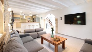 Ein modernes Wohnzimmer mit Couchtisch aus Holz, grauen Sofas und einem flachbildfernseher an der Wand.