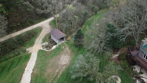 An aerial view of a rural property with a dirt road, a small wooden structure, and a fenced area with a deck. - Escape to Serenity at The Covered Bridge Hideaway-The Perfect Vacation Rental!
 (Fennimore)
