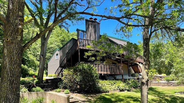 A rustic cabin with a wooden deck, a chimney, and a staircase leading to a second level. - Escape to Serenity at The Covered Bridge Hideaway-The Perfect Vacation Rental!
 (Fennimore)