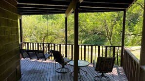 A wooden deck with two chairs and a table, overlooking a lush green landscape. - Escape to Serenity at The Covered Bridge Hideaway-The Perfect Vacation Rental!
 (Fennimore)