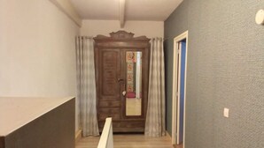 Um corredor com porta de madeira, parede azul e corrimão branco.