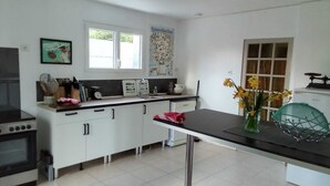 Cozinha com armários brancos, bancada preta, fogão e pia. Há uma janela com vista para árvores e uma parede com um mapa.