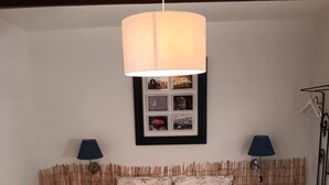 Quarto com cama, duas mesinhas de cabeceira, luminária pendente, quadro emoldurado e guarda-roupa.
