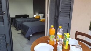 A hotel room with two beds, a table with breakfast items, and a view of the outside. - Idilliaco Inn (Motta Sant'Anastasia)