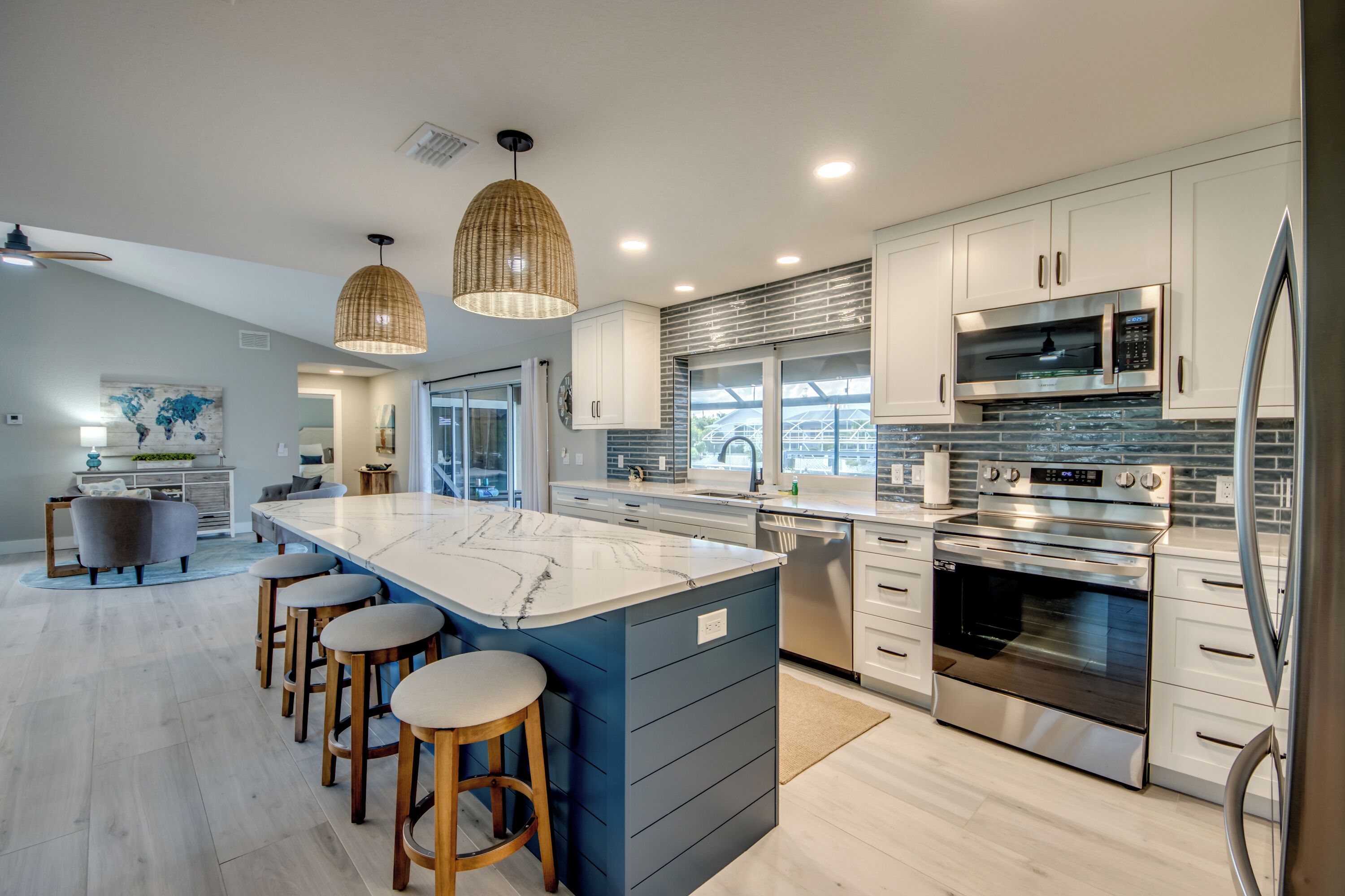 A modern kitchen with a large island, stainless steel appliances, and a world map artwork on the wall.