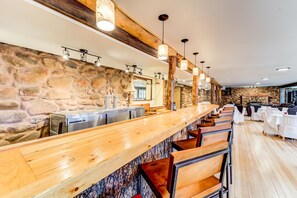 A bar area with a stone wall, wooden bar counter, and multiple seating options.