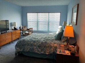 Enjoy a comfortable stay in this cozy room featuring a large bed, dresser, desk, and TV.