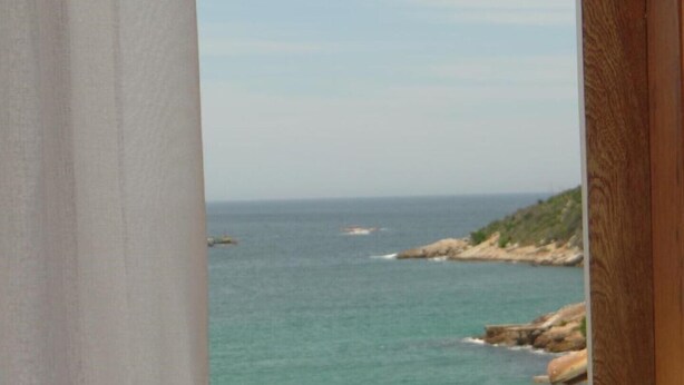 A coastal view through a window with a wooden frame.