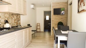 Une cuisine moderne avec des meubles blancs, un pare-feu en carreaux et un coin repas comprenant une table et des chaises.