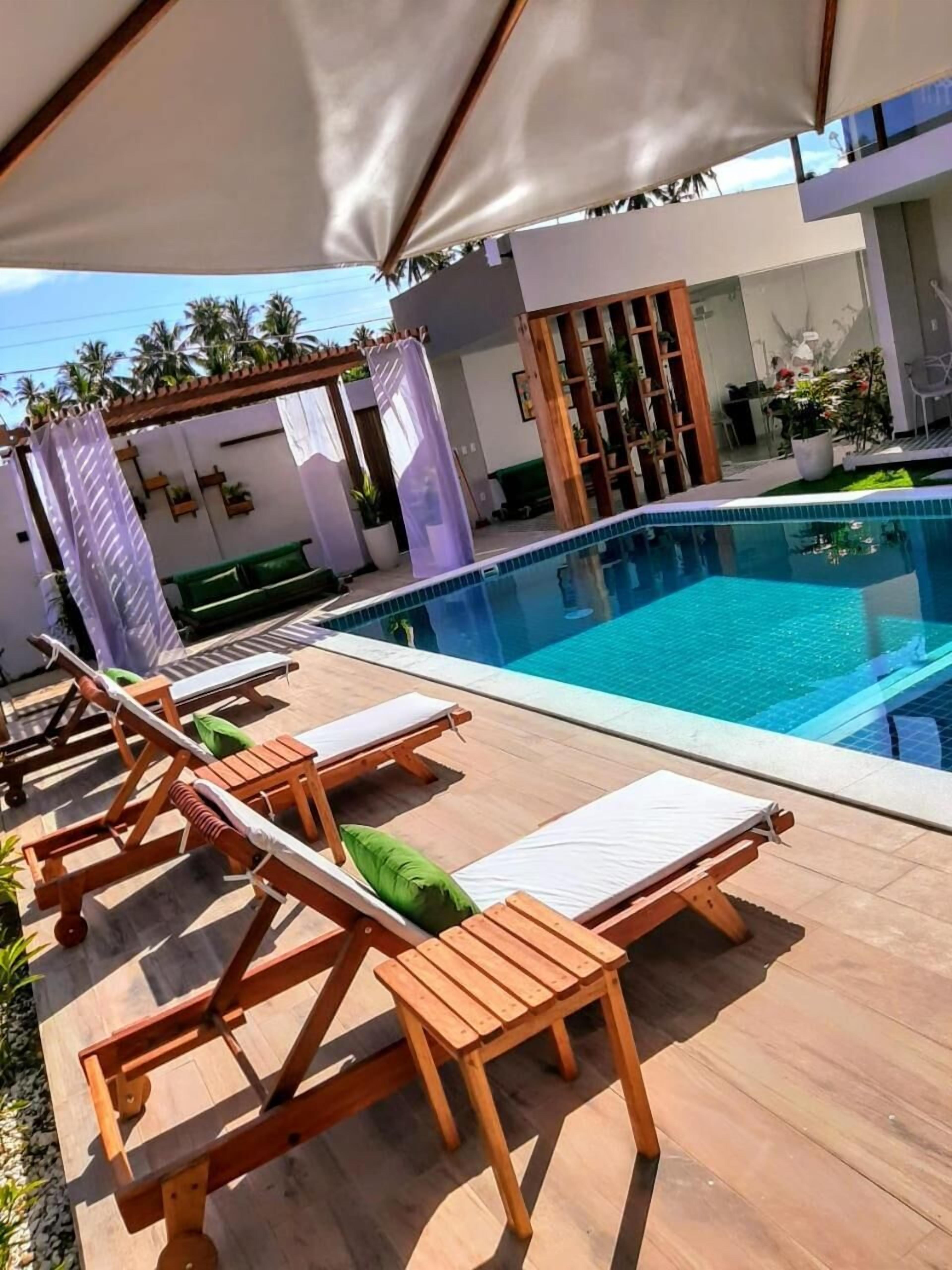 Un área junto a la piscina con sillones de madera.