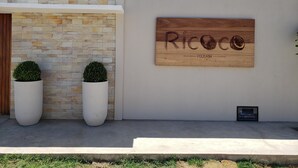 Fachada moderna de um edifício com parede de pedra e placa de madeira com a inscrição 