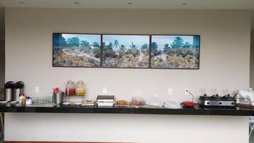 Une cuisine d’hôtel avec un buffet, comprenant un espace pour le café, des distributeurs de jus et une cuisinière.