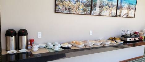 A buffet setup with various food items and condiments, a coffee machine, and a stove.