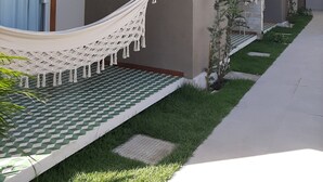 Um edifício moderno com telhado plano, uma rede e uma pequena área de jardim.