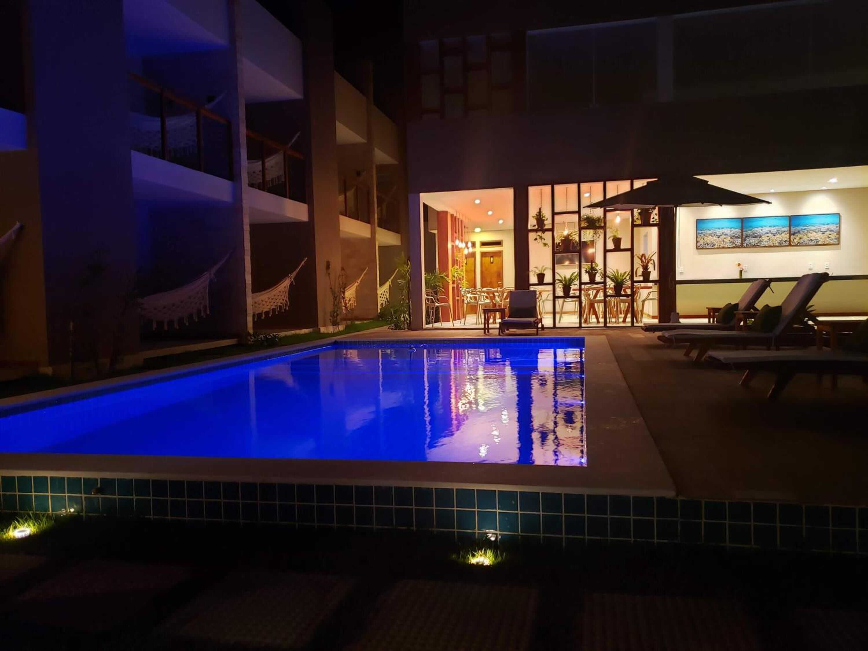 A swimming pool with lounge chairs and a dining area in the background.