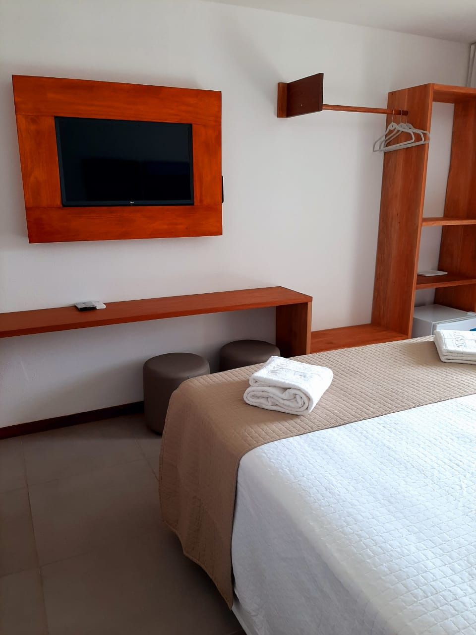 Een hotelkamer met een bed, een flatscreen televisie aan de muur, een houten plank en een zithoekje.