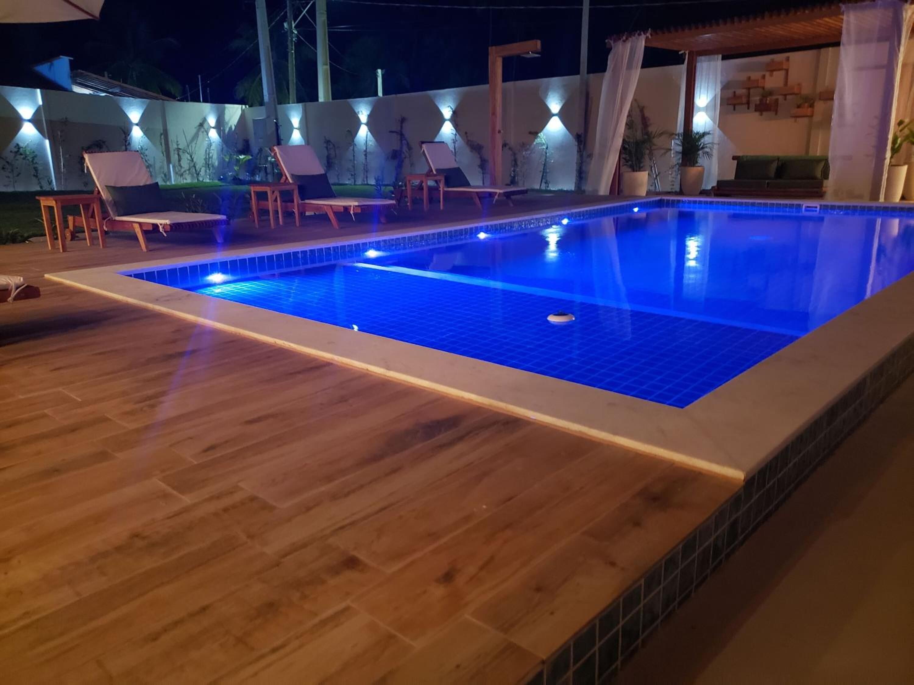 A swimming pool with a wooden deck and lounge chairs.