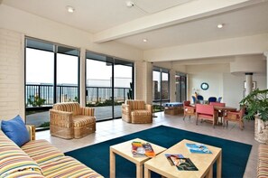 Relax in a spacious living area with a high ceiling and large windows offering a view of the outdoors.