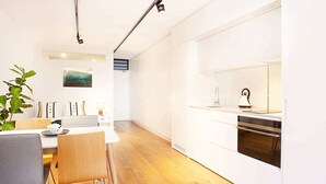 Een moderne keuken met witte kastjes, een ingebouwde oven en een waterkoker op het aanrecht.