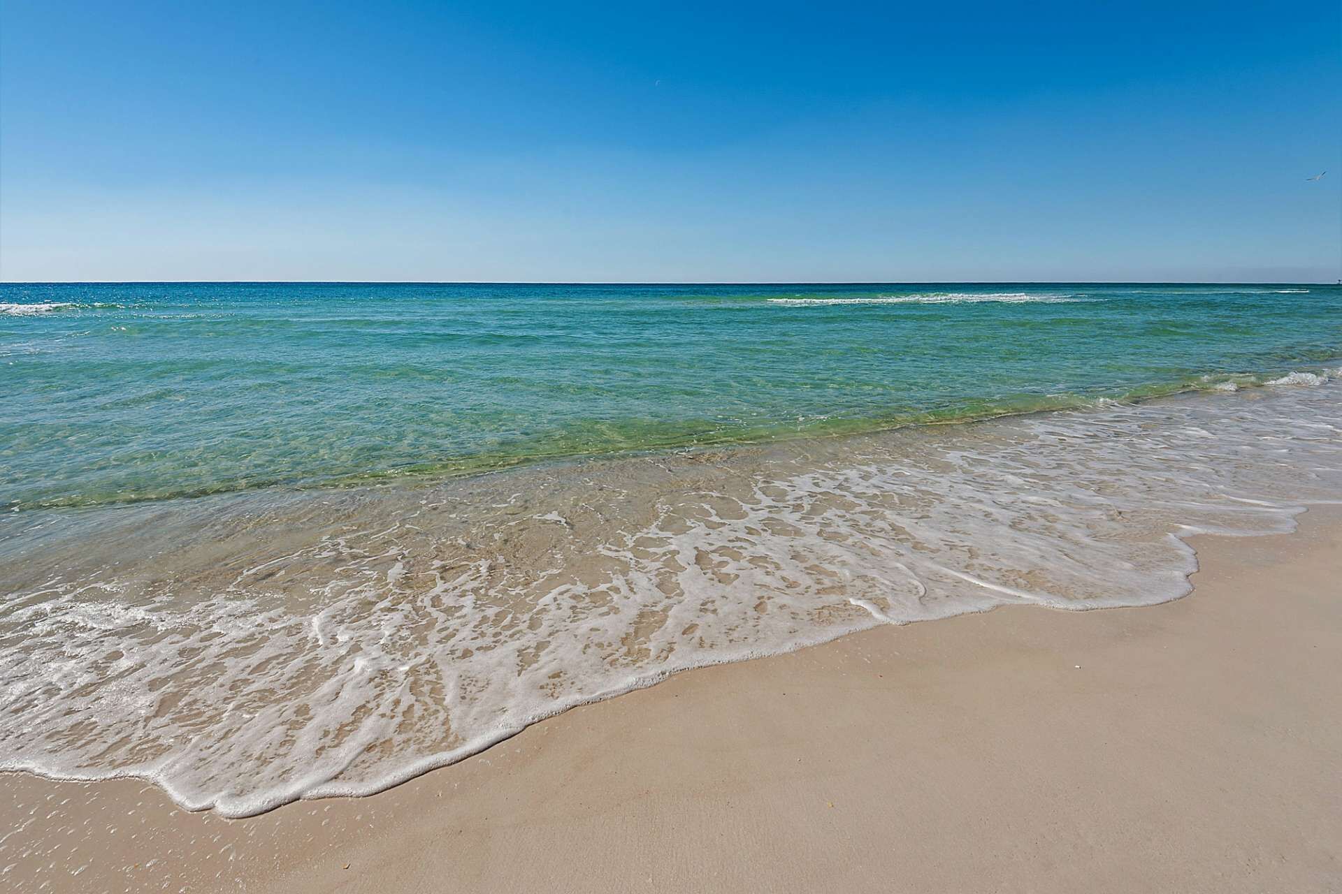 A beach with clear turquoise water and a sandy shore.