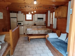 A compact cabin-style room with a kitchenette, a bed, and a small dining area. - Private apartment in a chalet at the base of the slopes, sleeps 5–7, south-facing terrace (Les Orres)