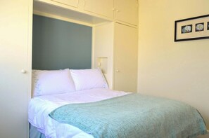 Ein Schlafzimmer mit einem Bett, einem Kleiderschrank und einem gerahmten Bild an der Wand.