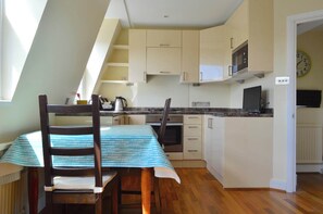 A kitchen with a dining table, chairs, cabinets, and a microwave.
