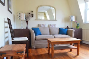 A living room with a sofa, two lamps, a mirror, and a wooden table.