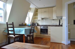 A kitchen with a dining table and chairs, a built-in oven, and a window.