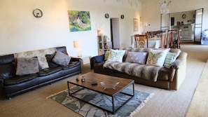 A living room with two sofas, a coffee table, and a rug. There is a painting on the wall and a lamp on a side table.