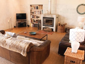 A cozy living room with a fireplace, a television, a bookshelf, and a comfortable seating area.