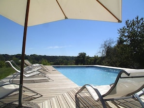 A wooden deck with lounge chairs and a pool.