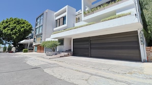 Ein modernes, mehrstöckiges Wohngebäude mit Garage, großen Fenstern und einem Baum im Vordergrund.