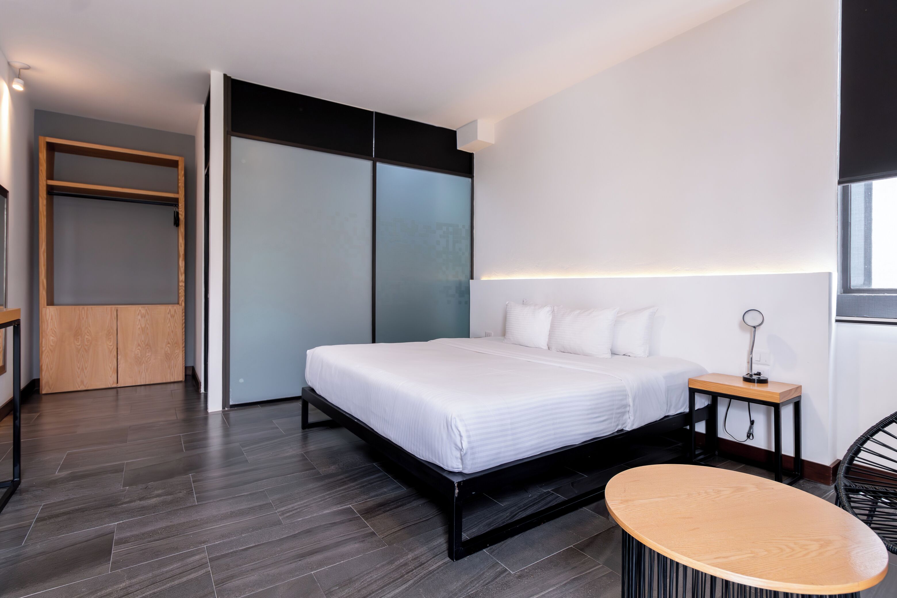 A modern bedroom with a large bed, a wooden nightstand, and a round table.