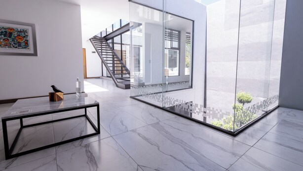 Ein modernes Interieur mit einer Glastrennwand, einer Treppe und einem Marmorboden.