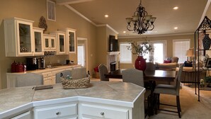 A spacious kitchen with white cabinetry, a central island, and a dining area with a red vase and chairs. - Relaxing Lake View Condo (Hot Springs)